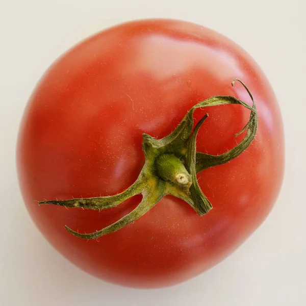 Eine rote Tomate sitzt auf einem weißen Tisch — Stockfoto