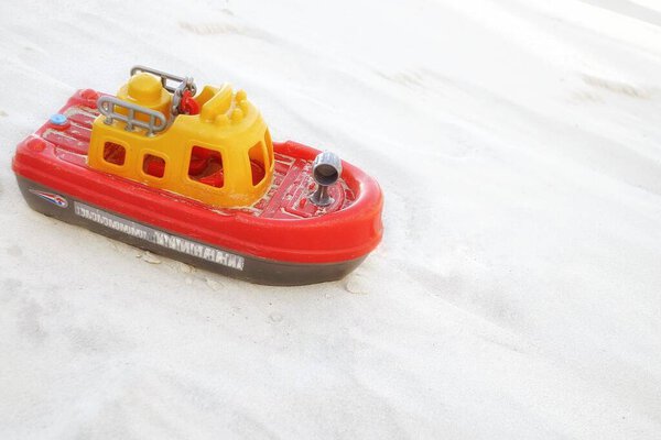 Childrens toy boat on the white sand.