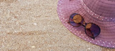 Güneş gözlüğü ve kumda bir şapka. Plaj tatil aksesuarları.