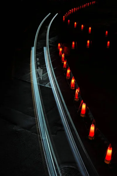 cool night time lapse of traffic cones and passing car light trails traveling around a slight curve surrounded by darkness. Minimalist night time long exposure of traffic cones and passing car light trails traveling around a slight curve in darkness.