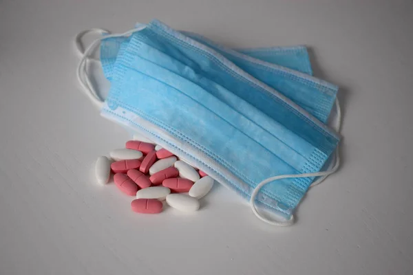 Tıbbi maskeli pembe ve beyaz haplar.