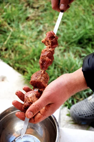 Adam metal kasenin üzerine salamura kebap dizmiş.