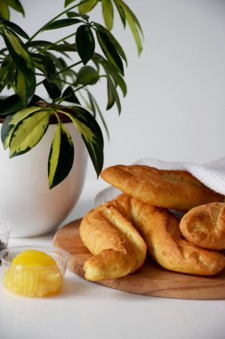 Beyaz mutfak peçetesinin altındaki fırından taze çıtır ekmekler. Şemsiye fabrikasının yanındaki tahta kesme tahtasında.