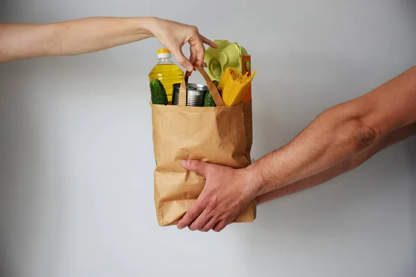 Çeşitli yiyeceklerle birlikte bağış torbası. Bakkal kuryesi kıza bir paket yemek veriyor. Elden ele. Karantina, çevrimiçi alışveriş veya bağış konsepti sırasında yiyecek teslimatı.