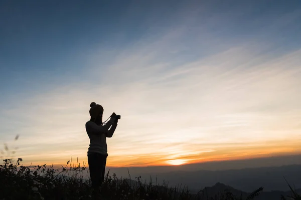 Siluetas de fotógrafo en acantilado contra cielo crepuscular colorido — Foto de Stock