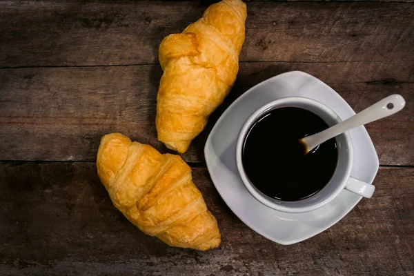 Frühstück mit Croissants und schwarzer Kaffeekomposition auf Holz — Stockfoto