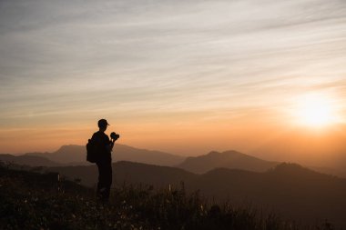 Fotoğrafçı siluetler renkli alacakaranlık gökyüzü karşı Cliff üzerinde