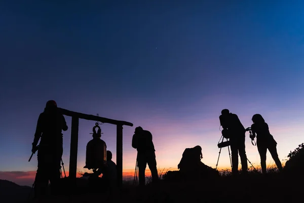 Fotógrafos siluetas en acantilado contra el cielo crepuscular colorido — Foto de Stock
