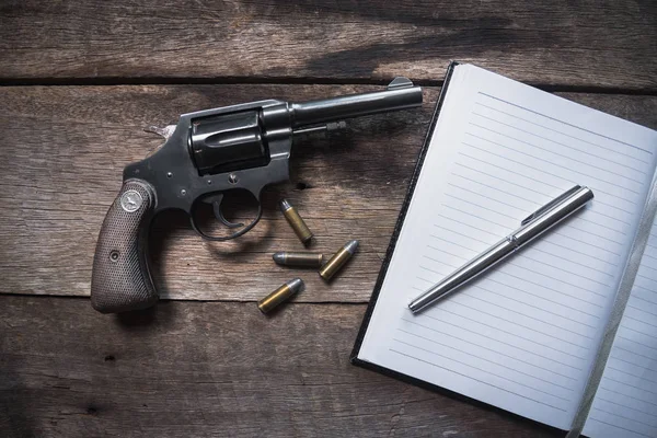 Όπλου και πυρομαχικών και κενό σημειωματάριο σε ξύλινο τραπέζι. το Top view — Φωτογραφία Αρχείου
