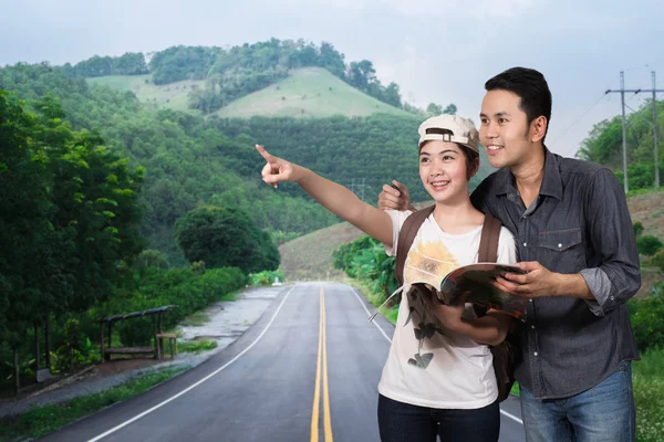 Feliz joven pareja de viajeros en la carretera de montaña — Foto de Stock