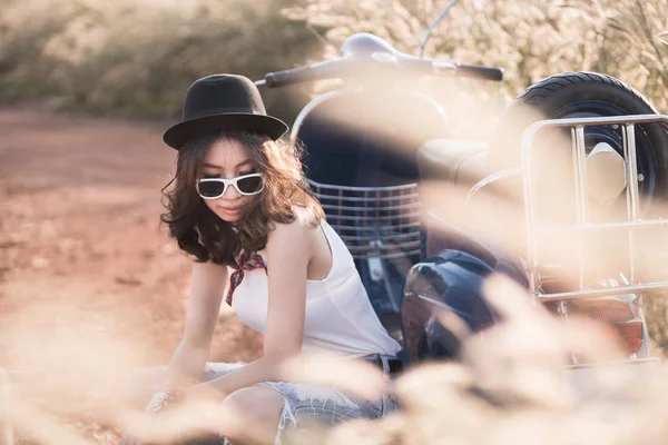 Junge Asiatin sitzt bei Sonnenuntergang auf Retro-Roller im Freien — Stockfoto