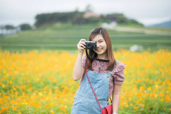 Ασιατικό κορίτσι πάρει φωτογραφία ανθισμένα κίτρινα λουλούδια, έννοια του ταξιδιού — Φωτογραφία Αρχείου