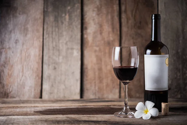 Bottiglia di vino, vetro e fiore bianco su sfondo di legno — Foto Stock