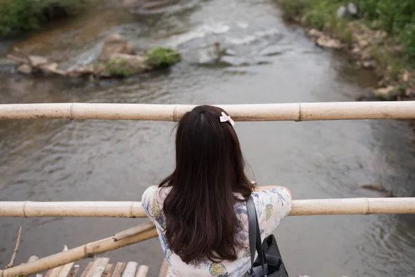 Unga Asien flicka sitter ensam på träbro har floden, resa con — Stockfoto