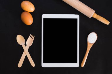 Pişirme kek malzemeler, tarif kitabı, ipad, un, yumurta, yumurta çırpıcı, oklava ve yumurta kabuğu koyu masada