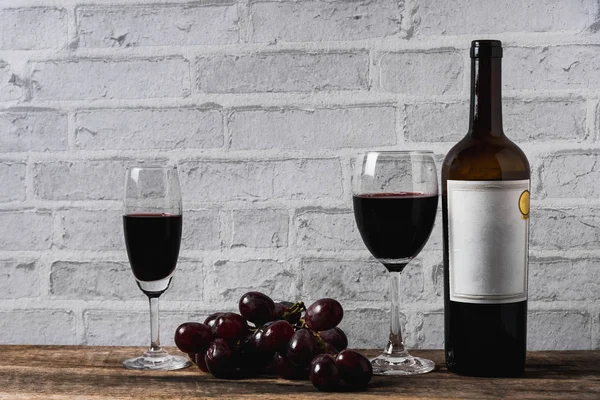 Vino e uva su tavola di legno sfondo mattone bianco — Foto Stock