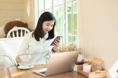 Çalışan kadınlar kafede cep telefonu ve laptop ile çalışıyorlar.