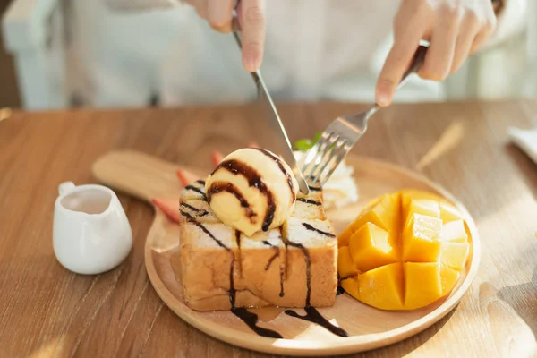 Close up de mão menina comer mel torrada na mesa de madeira no café — Fotografia de Stock