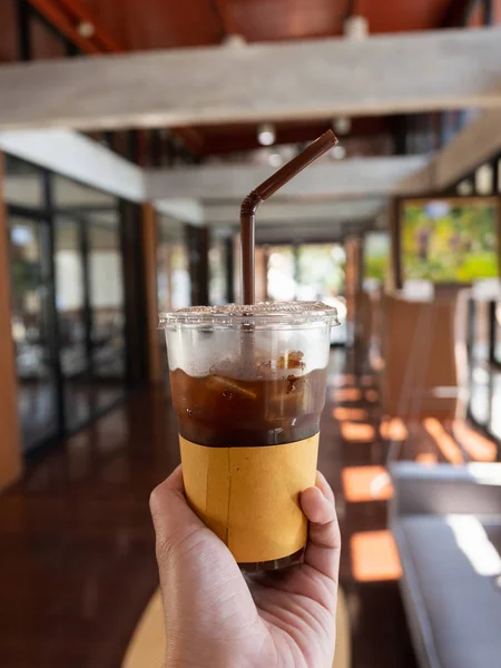 Hand holding ice coffee on cafe background — Stock Photo, Image