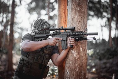 Terörist adam maske takıyor ve elinde silah tutuyor.