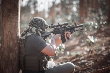 Terörist adam maske takıyor ve elinde silah tutuyor.