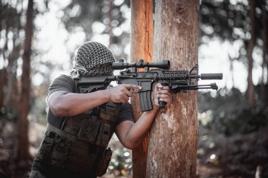 Terörist adam maske takıyor ve elinde silah tutuyor.