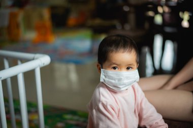 Cerrahi maske takan bebek evde kalsın. Covid-19 koronavirüs konsepti