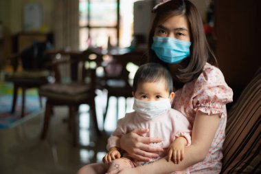 Cerrahi maske takan anne ve kızı evde kalıyor. Covid-19 koronavirüs konsepti