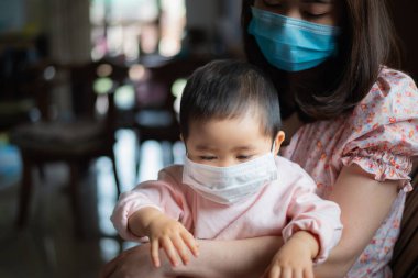 Cerrahi maske takan anne ve kızı evde kalıyor. Covid-19 koronavirüs konsepti