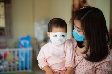 Cerrahi maske takan anne ve kızı evde kalıyor. Covid-19 koronavirüs konsepti