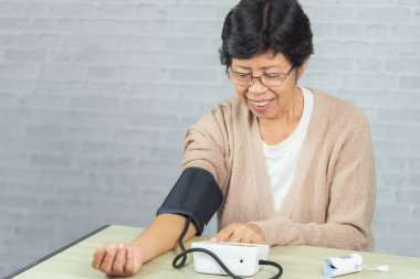 Tonometresi olan yaşlı kadın kan basıncını ölçüyor.