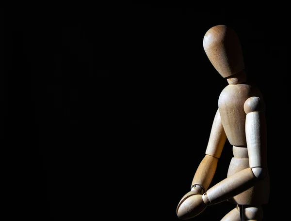 Ein Holzspielzeug Steht Mit Zusammengeklammerten Händen Auf Schwarzem Hintergrund — Stockfoto
