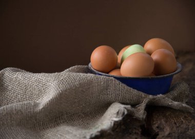 Çuval bezindeki eski mavi metal kasede kahverengi ve yeşil yumurtalar