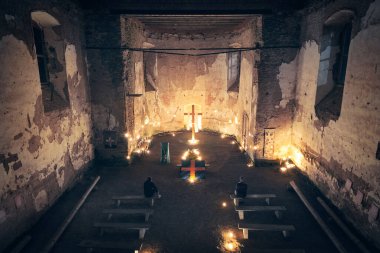 Gecenin içinde yanan mumlarla kilisenin içinde. İki dua eden adamla eski bir kilise..