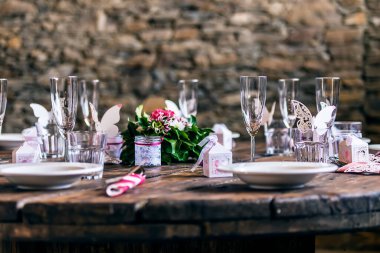 Ahşap masa ve taş zemin üzerinde boş bardaklar ve tabaklar ile dekore masa ayarları