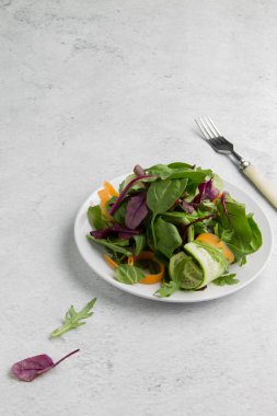 Beyaz arka planda salatalık ve havuçlu diyet yeşil salata. Yukarıdan minimalizm görünümü biçiminde dikey yönelimli resim ve kopyalama alanı