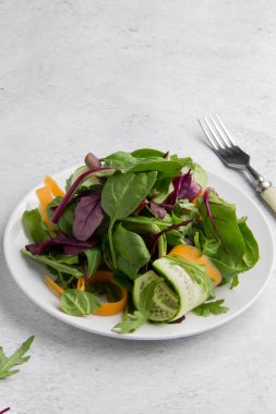 Beyaz arka planda salatalık ve havuçlu diyet yeşil salata. Yukarıdan minimalizm görünümü biçiminde dikey yönelimli resim ve kopyalama alanı