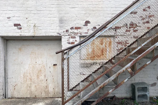 an alley warehouse loading and receiving door with rusted stairs to office