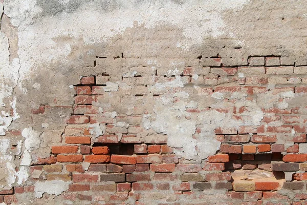 a beautiful old decaying concrete and red brick exterior wall exposed and falling apart