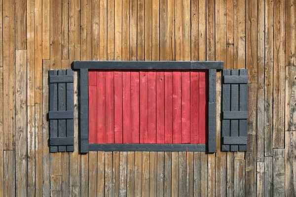 a bright red boarded pioneer farm barn window with shutters