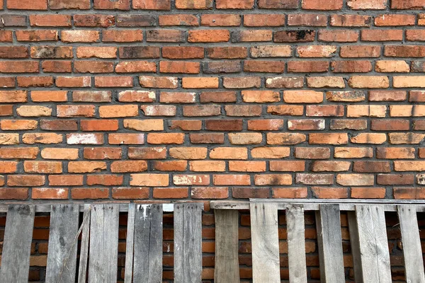 a vintage old red brick wall with leaning weathered pallets