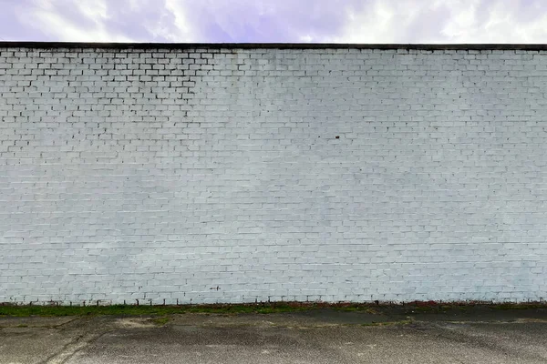 a white faded stone brick factory warehouse wall in an alley