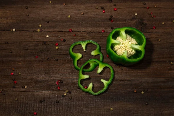 Green bell pepper sliced in rings on a wooden background