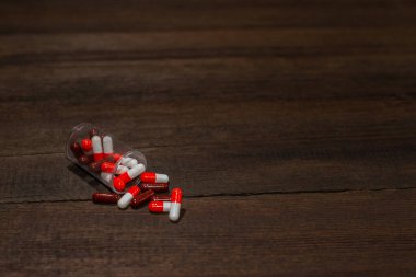 Ahşap arka planda kırmızı-beyaz ve kahverengi kapsül hapları. Eczane.