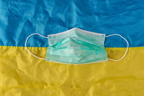 Disposable surgical protective mask on a blue and yellow background like the Ukrainian flag. New coronavirus in Ukraine