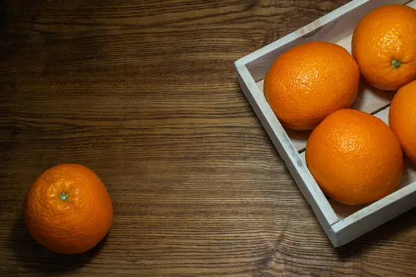 木製の表面の背景に箱の中のオレンジ色の果物を熟す — ストック写真