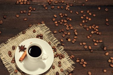 Kahve fincanı, tahtadan arka planda tarçınlı kahve çekirdekleri.