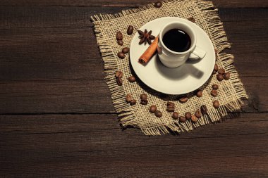 Kahve fincanı, tahtadan arka planda tarçınlı kahve çekirdekleri.