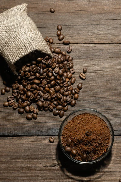 Grains of freshly roasted coffee and ground coffee on a wooden background. The texture of coffee beans.