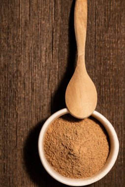 Beyaz bir seramik kasede koyu bir zeminde tarçın.